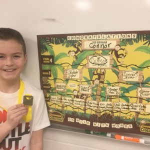 Student stands in front of a bananagrams challenege poster