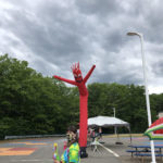 Parking lot with people celebrating, am inflatable waving person, and an easy up in the parking lot at Hooksett Memorial School